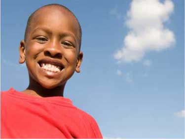 boy smiling with blue sky and one cloud in background