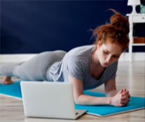 woman in plank position looking at laptop