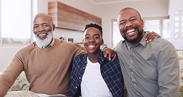 Three generations of men pose with arms on one another's shoulder