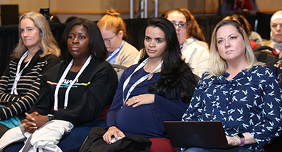 four women in audience listening to speakers